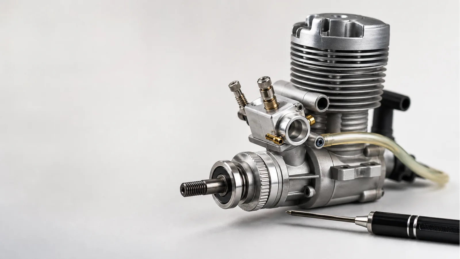 Miniature model engine with its carburetor needle valves visible on a clean engineering bench